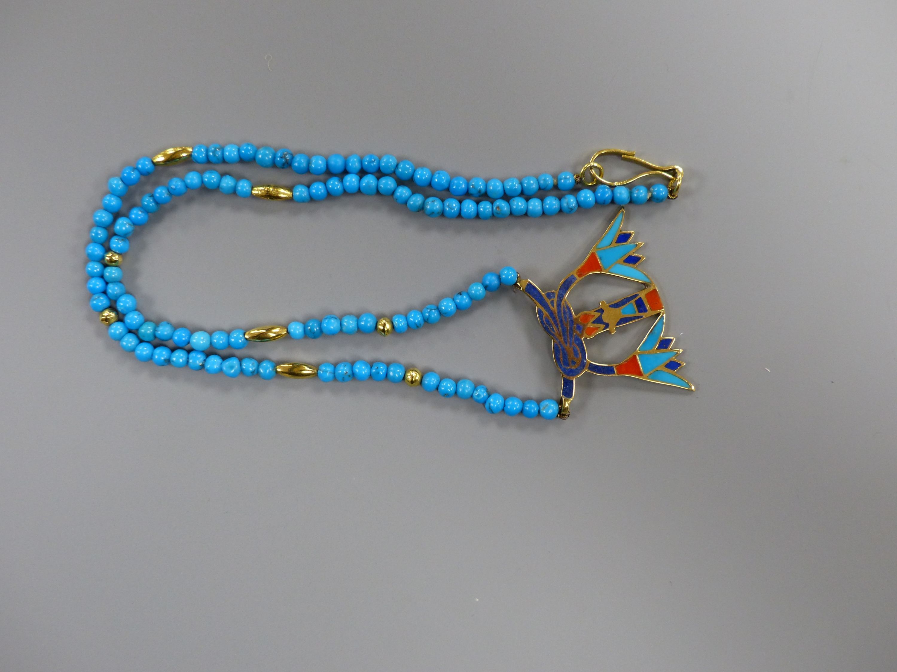 An Egyptian enamelled yellow metal pendant on turquoise and yellow metal bead necklace, the clasp marked 750, 54cm,